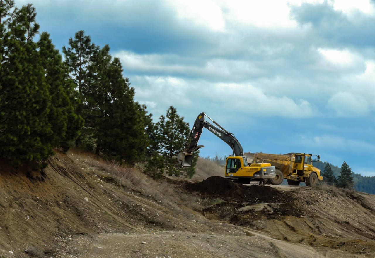 Services-02 Excavator and truck working at a construction site in Coeur d'Alene, Idaho with cloudy skies.