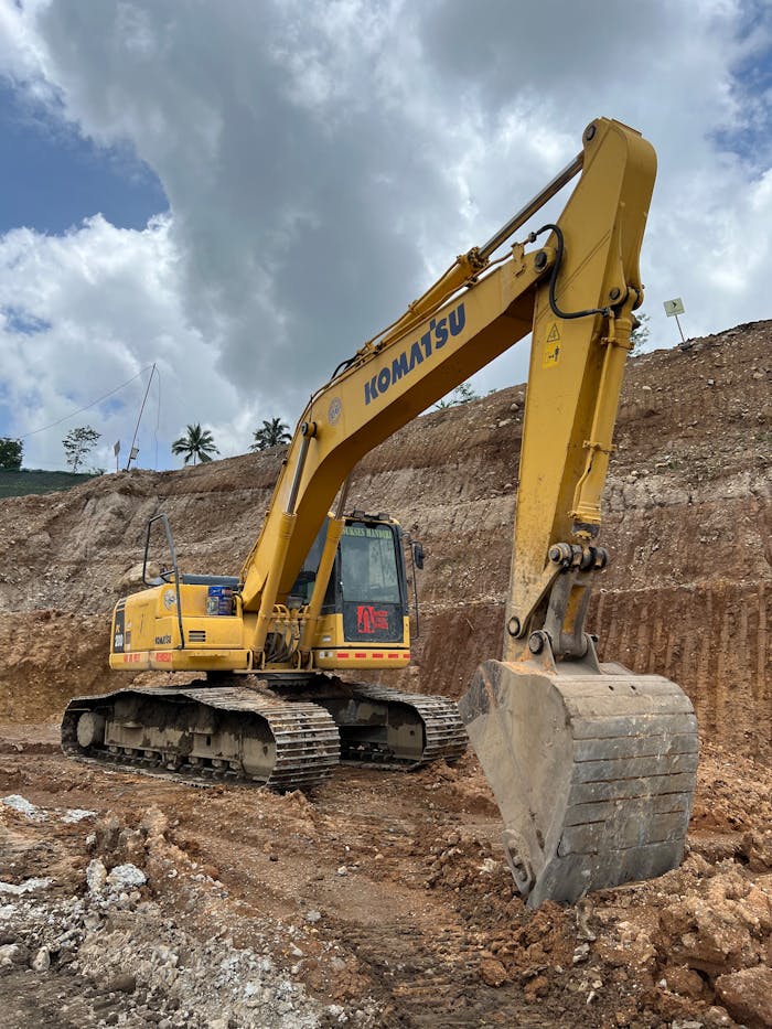 Yellow Komatsu bulldozer working at a construction site in Surakarta, Central Java under a cloudy sky.