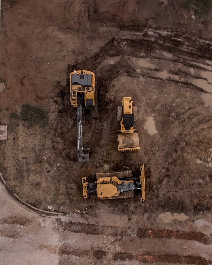 creative An aerial shot of heavy machinery at a construction site, including excavators and road rollers.