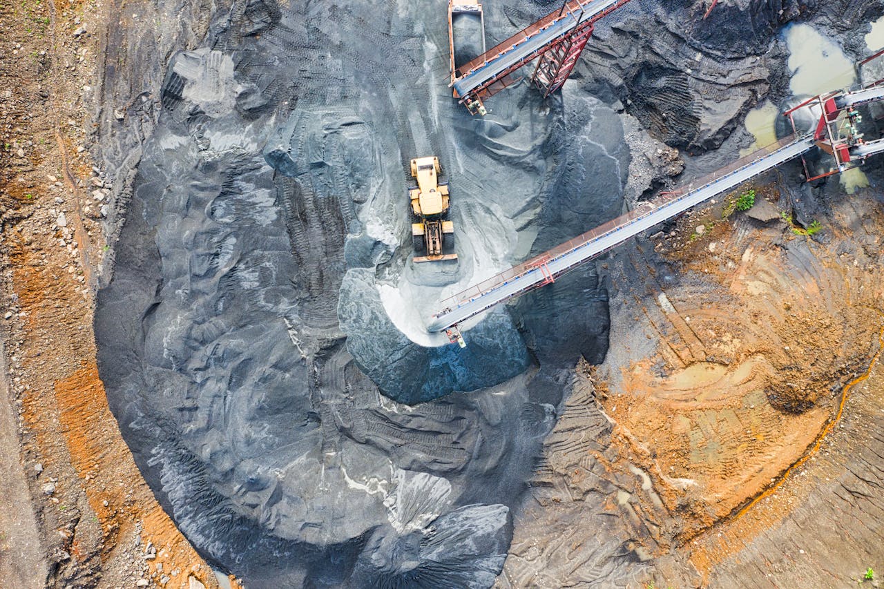 why-choose-us Aerial view of a large industrial mining site with heavy machinery and conveyor belts in operation.